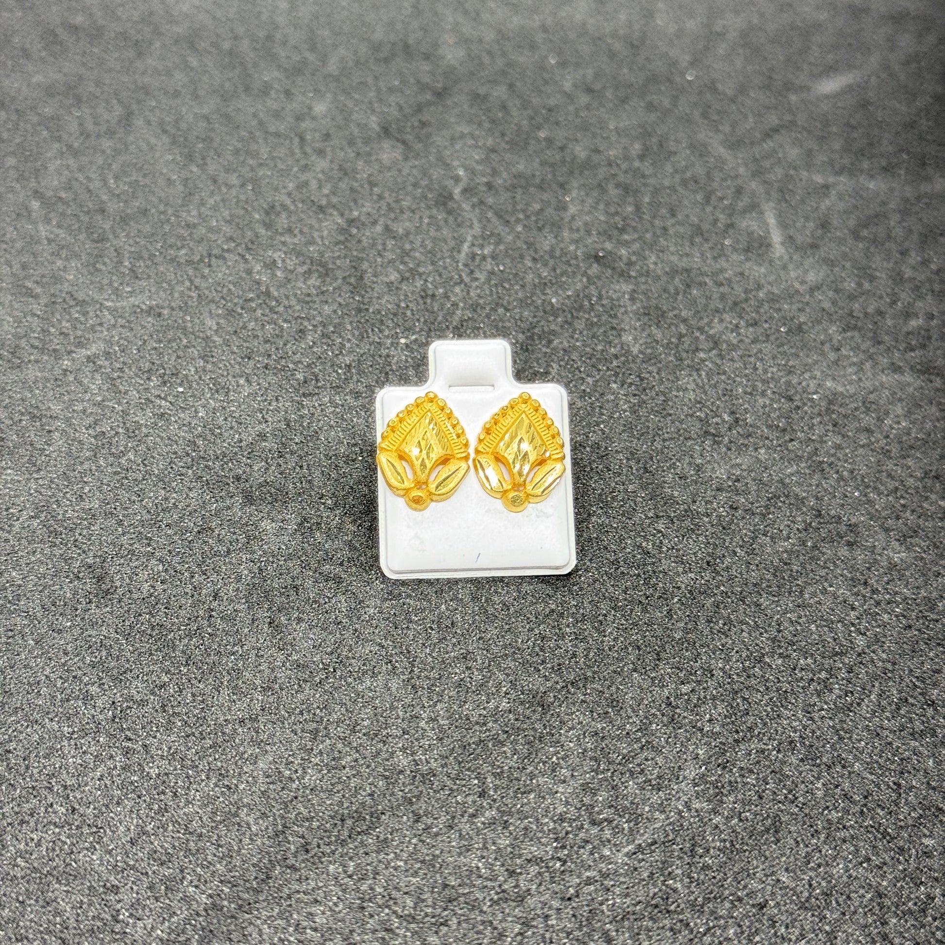 Gold earrings on a gray surface