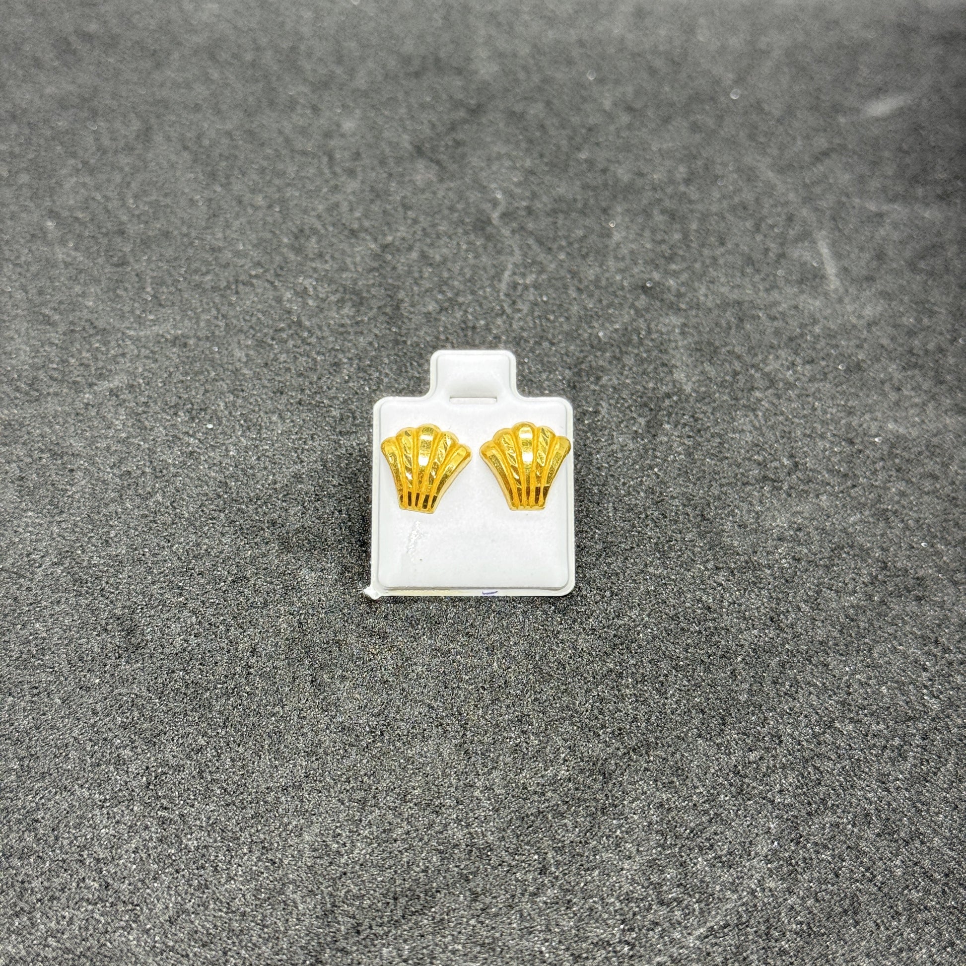 Gold earrings on a gray surface