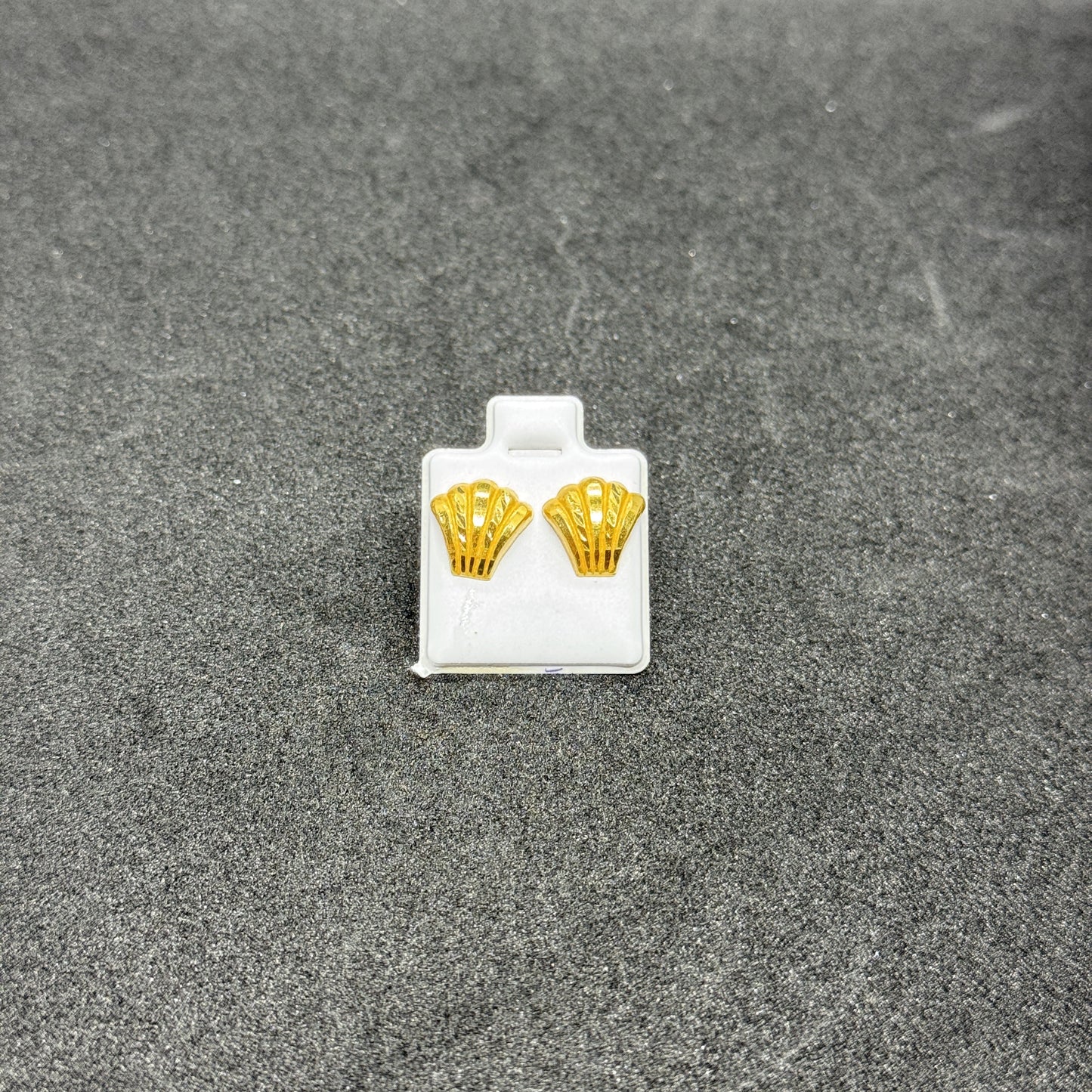 Gold earrings on a gray surface